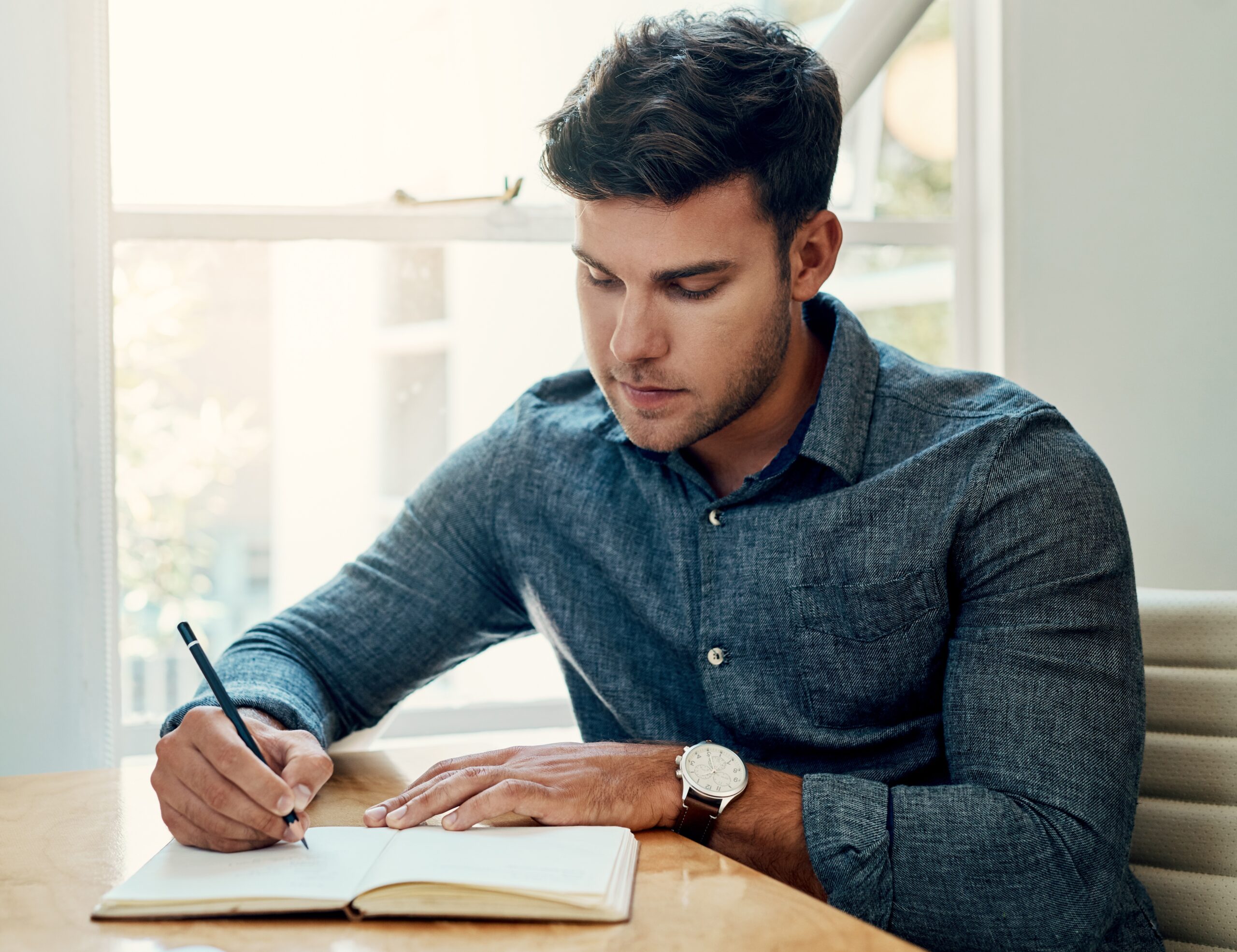 A man writing thoughtfully in a notebook with pen and paper—highlighting the creative power of analog tools in a digital world.