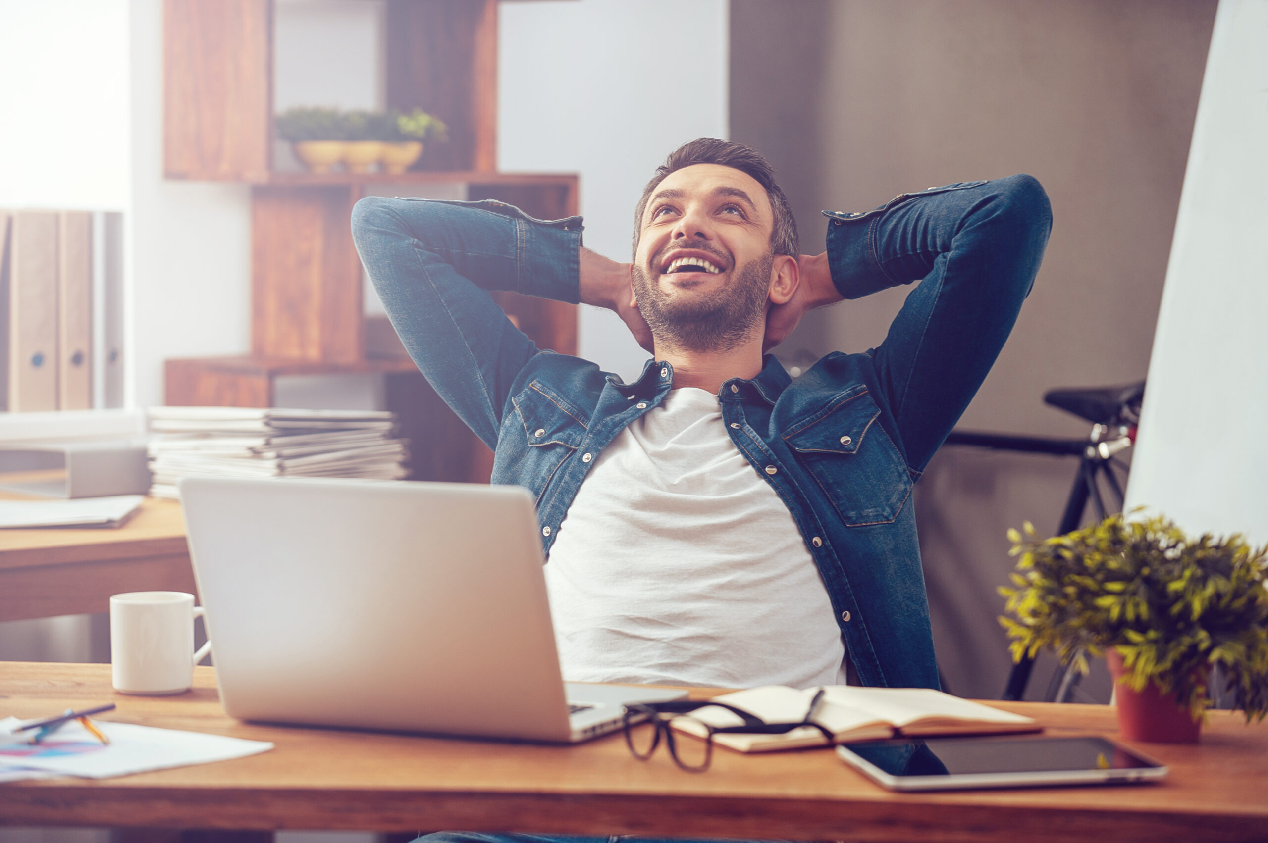 A smiling man leaning back at his desk, looking inspired and relaxed—capturing the joy of a daily creative breakthrough.